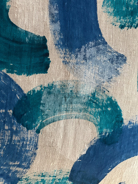 Abstract painterly fabric pattern with broad brushstrokes in deep blue, teal, and turquoise on a warm beige linen-textured background.